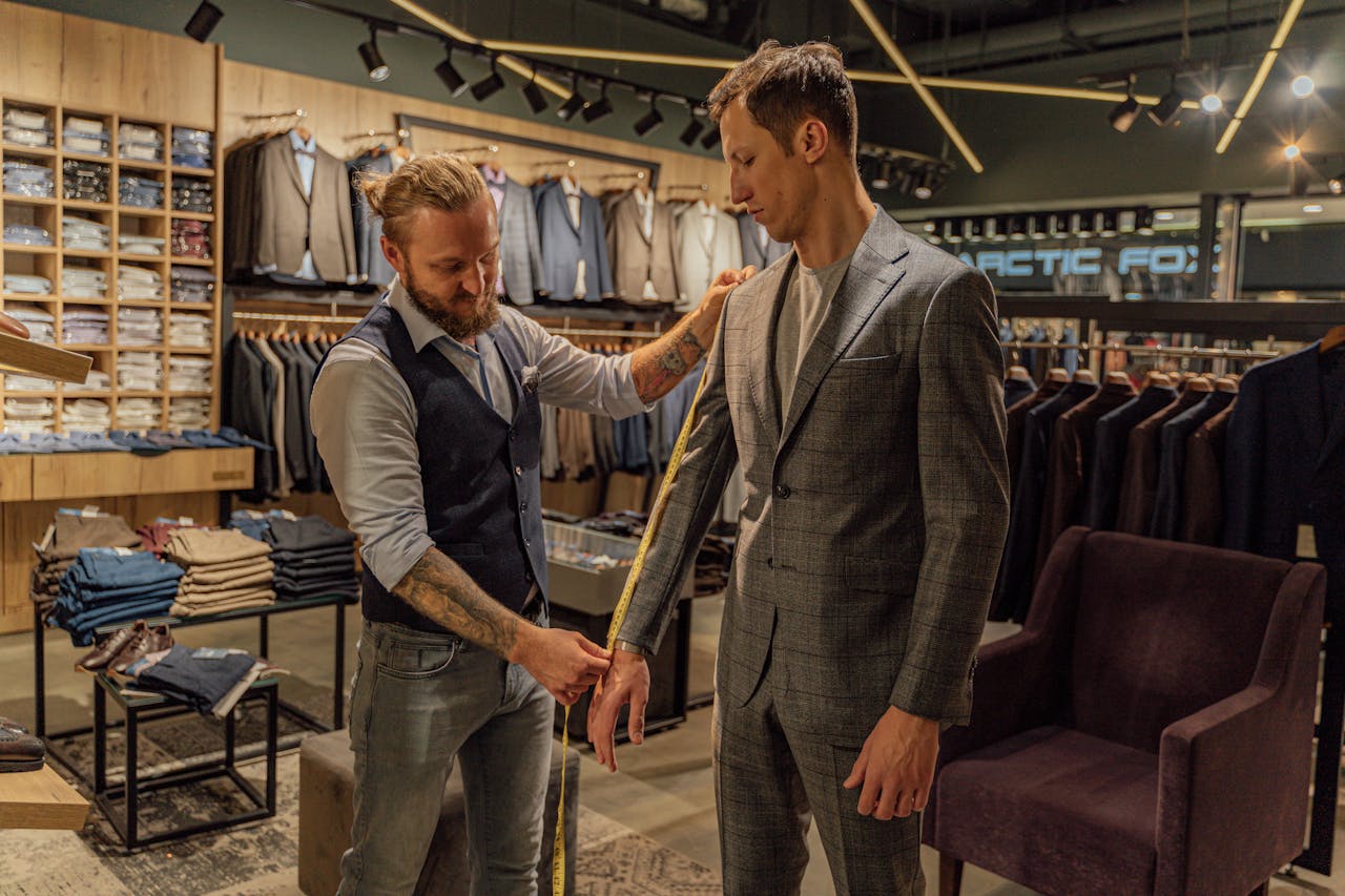 Tailor measuring a customer in a suit store for a perfect fit.
