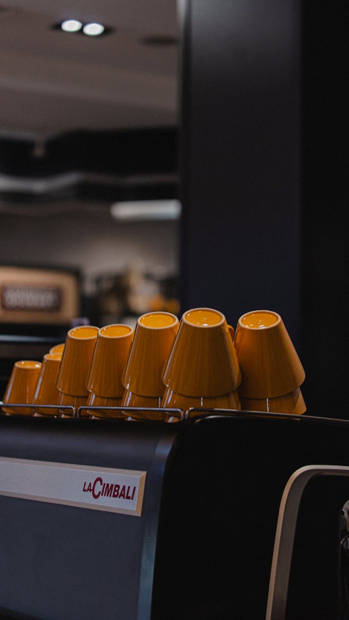 services-01 Stylish yellow cups arranged on an espresso machine in a modern café interior.